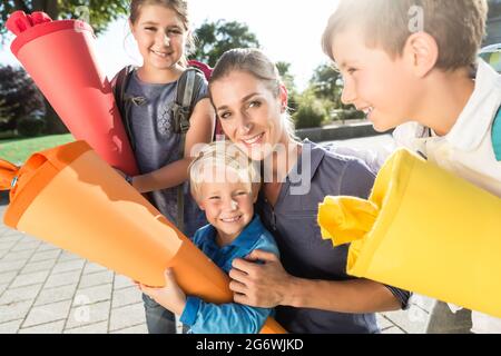 Frau und Kinder an der Einschreibung Tag mit Schule Kegel Stockfoto