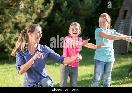 Glückliche Mutter mit Kindern Töchter tun Tanz Übung im Freien Stockfoto