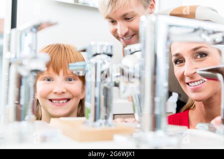 Porträt einer glücklichen Familie, die in einem modernen Sanitärgeschäft mit hochwertigen Armaturen und Geräten nach einem neuen Waschbecken sucht Stockfoto