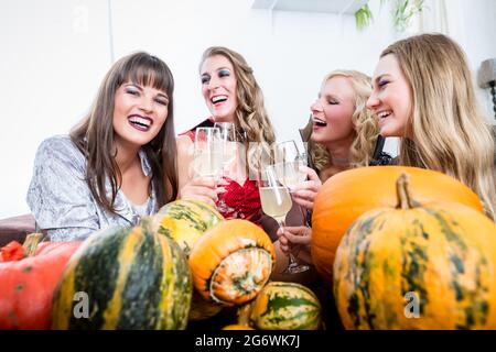 Junge und schöne Frau posiert lustig und beängstigend beim Toasting mit ihren besten Freunden während Halloween Kostüm Party Stockfoto