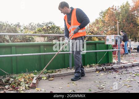 Mann fegen den Boden des Recycling-Zentrum nach der Lieferung von Abfall grün in Container Stockfoto