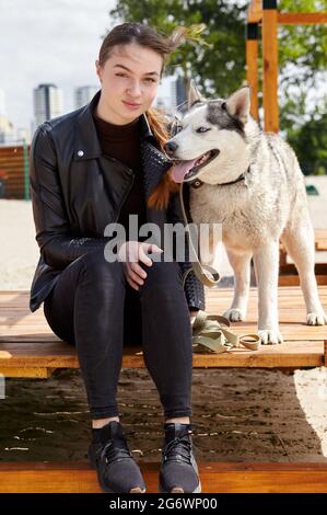 Besitzer Mädchen ruhen mit einem Husky Hund im Park. Freundschaft eines Hundes und einer Frau Stockfoto