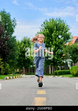 Ein Mädchen in Schuluniform und Rucksack läuft entlang der Straße zum Park, dem Konzept des Schuljahres Stockfoto