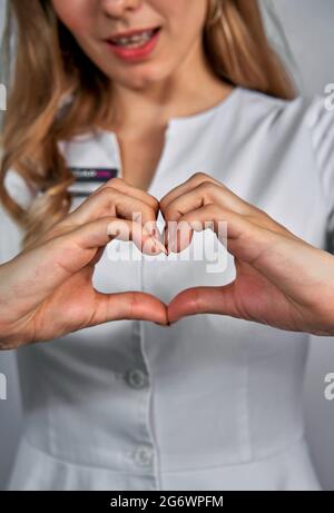 Nahaufnahme von zwei weiblichen kaukasischen Händen isoliert auf weißem Hintergrund. Junge Frau formt mit ihren Fingern Herzform. Horizontale Farbfotografie Stockfoto