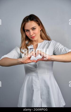 Nahaufnahme von zwei weiblichen kaukasischen Händen isoliert auf weißem Hintergrund. Junge Frau formt mit ihren Fingern Herzform. Horizontale Farbfotografie Stockfoto