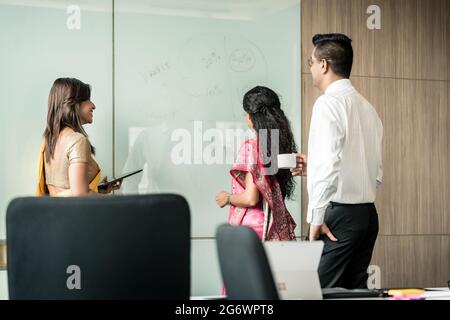 Drei kreative indischen Kollegen Ideen schriftlich beim Brainstorming im Inneren eines modernen Büros Stockfoto