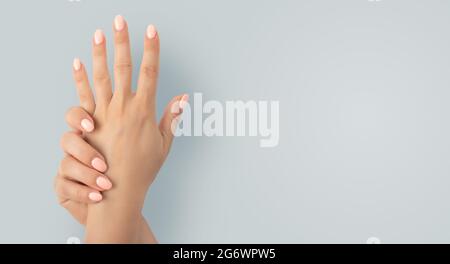 Schöne weibliche Hände mit stilvollem Maniküre-Gel-Nagellack auf grauem Hintergrund. Nahaufnahme der Frau mit schönen Händen auf grauem Hintergrund, Raum Stockfoto