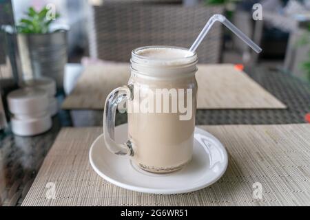 RAF-Kaffee, russische Spezialität, mit mit Espresso und Zucker gepeitschter Creme, serviert in einem runden Glas mit Stroh, auf einem weißen Teller Stockfoto