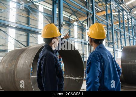 Facharbeiter nach oben zeigen, während die Anweisungen an einen Lehrling in einer Fabrik Herstellung Kessel Stockfoto