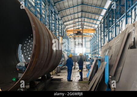 Zwei Arbeiter tragen gelb Schutzhelm und blaue uniform im Inneren einer Industriehalle Stockfoto