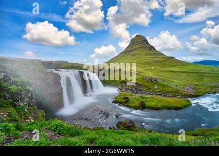 Landschaftsansicht von Kirkjufellsfoss bei Tag, blauer Himmel und schöne Wolken. Der Wasserfall ist berühmt und ein beliebter Touristenort in Island. Stockfoto