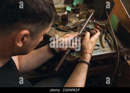 Ein Juwelier repariert einen goldenen Diamantring in seiner Werkstatt, Arbeitsprozess Stockfoto