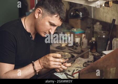 Der Juwelier inspiziert den Goldring in seiner Werkstatt auf Mängel Stockfoto