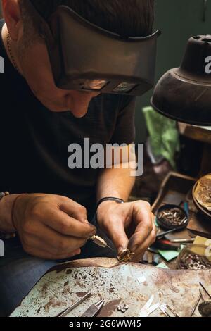 Der Juwelier repariert Goldschmuck in seiner Werkstatt, untersucht den Ring auf Mängel Stockfoto