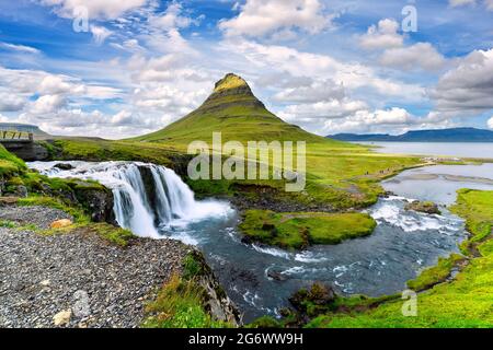 Landschaftsansicht von Kirkjufellsfoss bei Tag, blauer Himmel und schöne Wolken. Der Wasserfall ist berühmt und ein beliebter Touristenort in Island. Stockfoto