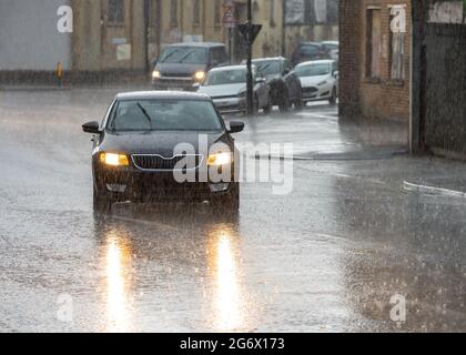 Starker Regen Sturm und überflutete Straßen Autos fahren in Regenlicht auf Reflektion im Wasser der Straßen der Stadt. Überschwemmung und Gefahr von Aquaplaning stehen Stockfoto