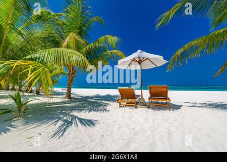 Wunderschöne tropische Insellandschaft, zwei Sonnenliegen, Liegen, Sonnenschirm unter Palmen. Weißer Sand, Meerblick mit Horizont, idyllisch blauer Himmel, Ruhe Stockfoto