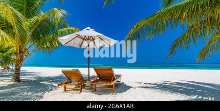 Wunderschöne tropische Insellandschaft, zwei Sonnenliegen, Liegen, Sonnenschirm unter Palmen. Weißer Sand, Meerblick mit Horizont, idyllisch blauer Himmel, Ruhe Stockfoto