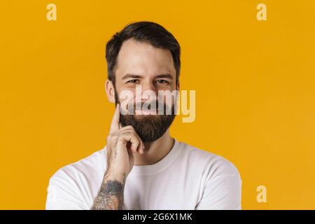 Lächelnder, brünett bärtiger Mann, der auf die Kamera schaut, die auf gelbem Hintergrund steht Stockfoto
