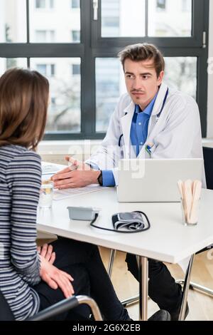 Junge gewidmet Arzt Holding eine X-ray beim Hören mit Aufmerksamkeit für seine weiblichen Patienten während einer privaten Beratung im Büro Stockfoto