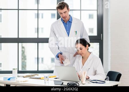 Erfahrenen Arzt und Apotheker Kontrolle zusammen elektronische Informationen auf einem Laptop im Büro eines Krankenhauses mit moderner Ausstattung. Stockfoto