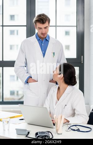 Erfahrenen Arzt und Apotheker Kontrolle zusammen elektronische Informationen auf einem Laptop im Büro eines Krankenhauses mit moderner Ausstattung. Stockfoto