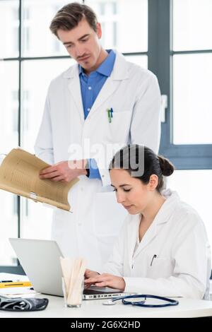 Erfahrenen Arzt und Apotheker Kontrolle zusammen elektronische Informationen auf einem Laptop im Büro eines Krankenhauses mit moderner Ausstattung. Stockfoto