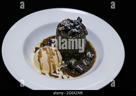 Klebriger Toffee-Pudding mit Vanilleeis, Karamellsauce und Keksflocken Stockfoto