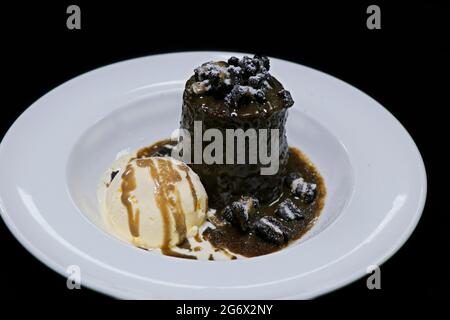 Klebriger Toffee-Pudding mit Vanilleeis und Karamellsauce in einer weißen Servierplatte Stockfoto