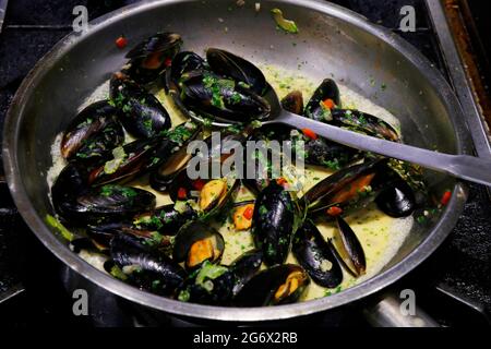 Miesmuscheln, bekannt als Moules a la marinara, in einer heißen Pfanne beim Kochen Stockfoto