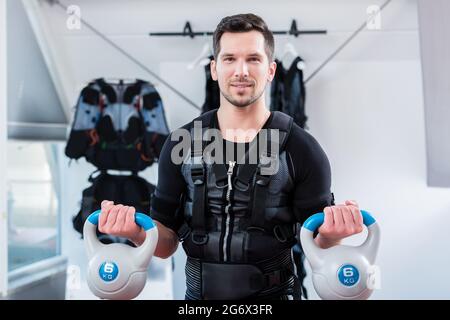 Starker Mann in ems-Fitnessstudio, der Fitness-Training mit Gewichten macht, die auf die Kamera schauen Stockfoto