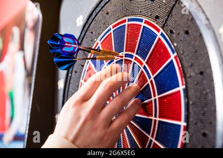 Nahaufnahme der Hand einer Person, die Pfeile von der Dartscheibe entfernt Stockfoto