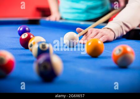 Nahaufnahme der Hand eines Mannes, der Billard auf einem blauen Billardtisch spielt Stockfoto