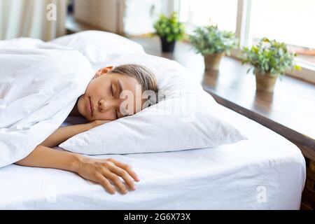 Ein 10-jähriges Mädchen, das vor dem Erwachen unter einer Decke schläft. Stockfoto