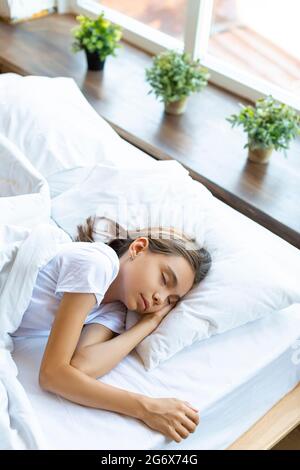Ein 10-jähriges Mädchen, das vor dem Erwachen unter einer Decke schläft. Stockfoto