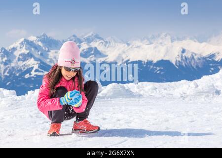 Innsbruck, Österreich - 11. April 2015 - ein glückliches junges Mädchen macht Schneeball im Skigebiet Nordkette in Innsbruck, Österreich Stockfoto