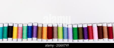 Satz mehrfarbiger Fadenumfänge auf weißem Hintergrund mit Textstelle. Näh- oder Schneiderei, für Werbung Stockfoto