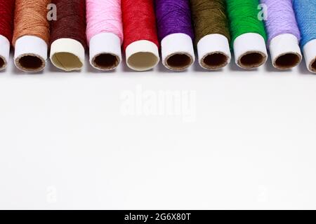 Satz mehrfarbiger Fadenumfänge auf weißem Hintergrund mit Textstelle. Näh- oder Schneiderei, für Werbung Stockfoto