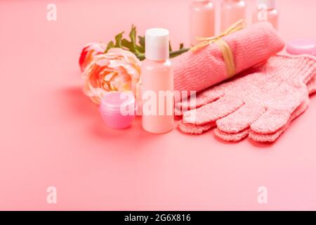 Pumpflaschen, Dispenser, Cremetöhrchen, rosa Handschuhe und Handtuch auf rosa Hintergrund. Spa, Behandlung und gesundes Lifestyle-Konzept. Reisegröße Kosmetik pa Stockfoto