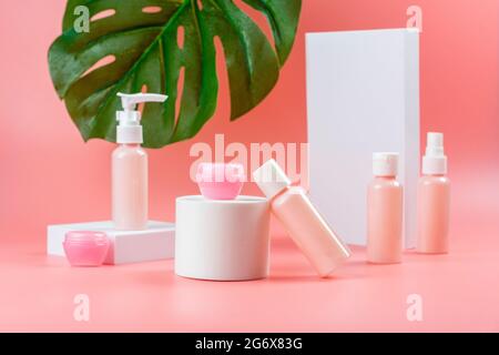 Pumpflaschen, Dispenser, Cremetöhrchen, rosa Handschuhe und Handtuch auf rosa Hintergrund. Spa, Behandlung und gesundes Lifestyle-Konzept. Reisegröße Kosmetik pa Stockfoto