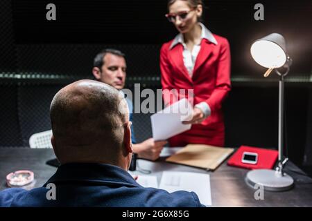 Rückansicht eines mittleren Alters vermuten oder Zeugnis am Schreibtisch während der polizeilichen Vernehmung vor der Staatsanwaltschaft und eine weibliche Rechtsanwalt sitzen Stockfoto