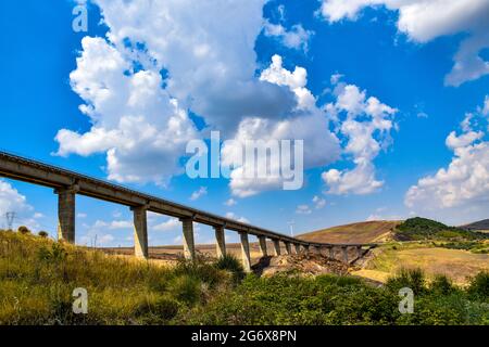 Autobahn auf der Überführung, die an einem sonnigen Tag durch ein grasbewachsenes Tal führt Stockfoto