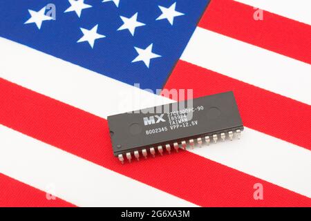 Nahaufnahme von Macronix International Integrated Circuit / EPROM Chip auf kleiner US Stars & Stripes Flagge. Für US-Halbleiterknappheit im Jahr 2021. Stockfoto