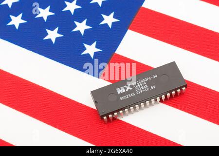 Nahaufnahme von Macronix International Integrated Circuit / EPROM Chip auf kleiner US Stars & Stripes Flagge. Für US-Halbleiterknappheit im Jahr 2021. Stockfoto