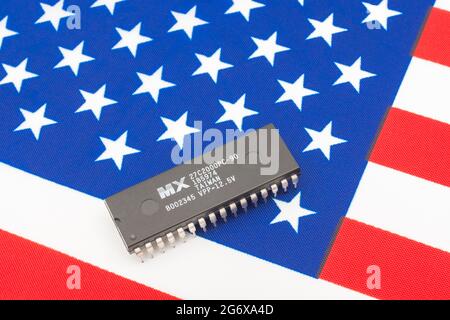 Nahaufnahme von Macronix International Integrated Circuit / EPROM Chip auf kleiner US Stars & Stripes Flagge. Für US-Halbleiterknappheit im Jahr 2021. Stockfoto