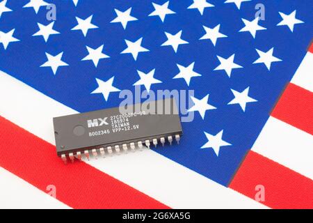 Nahaufnahme von Macronix International Integrated Circuit / EPROM Chip auf kleiner US Stars & Stripes Flagge. Für US-Halbleiterknappheit im Jahr 2021. Stockfoto