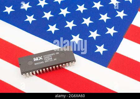 Nahaufnahme von Macronix International Integrated Circuit / EPROM Chip auf kleiner US Stars & Stripes Flagge. Für US-Halbleiterknappheit im Jahr 2021. Stockfoto