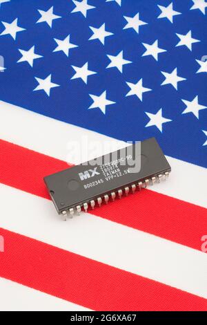 Nahaufnahme von Macronix International Integrated Circuit / EPROM Chip auf kleiner US Stars & Stripes Flagge. Für US-Halbleiterknappheit im Jahr 2021. Stockfoto