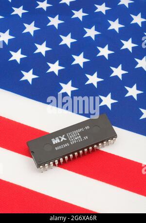 Nahaufnahme von Macronix International Integrated Circuit / EPROM Chip auf kleiner US Stars & Stripes Flagge. Für US-Halbleiterknappheit im Jahr 2021. Stockfoto