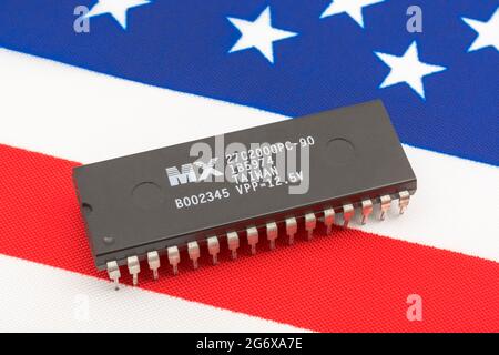 Nahaufnahme von Macronix International Integrated Circuit / EPROM Chip auf kleiner US Stars & Stripes Flagge. Für US-Halbleiterknappheit im Jahr 2021. Stockfoto